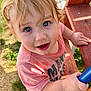 toddler, child, blue_eyes, blonde_hair, pink_shirt, outdoor, playground, climbing, hand, face, curious, grass, wooden_structure, metal_rail, daylight, casual_clothing, expression, portrait, young_child, nature