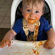 Maddox is registered to the contest to win money with this photo: toddler, child, high_chair, messy, baby_food, face, hands, blue_eyes, clothing, feeding_time, indoor, expression, cute, smile, hair, tray, food, seat, straps, person