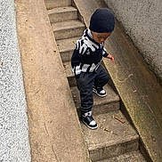 Kenan a rejoint le concours — aidez-le/la à gagner de superbes lots ! child, boy, stairs, concrete, outdoor, black_hat, black_white_sweater, sneakers, urban, sidewalk, railing, pavement, casual_clothing, fall, winter, young, walking, curious, street, daytime