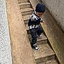 child, boy, stairs, concrete, outdoor, black_hat, black_white_sweater, sneakers, urban, sidewalk, railing, pavement, casual_clothing, fall, winter, young, walking, curious, street, daytime