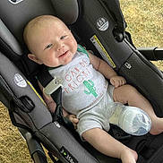 Eli joined the competition — help win amazing prizes! baby, car_seat, bottle, outdoor, grass, onesie, smiling, child, infant, seatbelt, happy, cactus, milk, foot, hand, person, clothing, baby_bottle, seat, resting