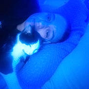 Tux is registered to the contest to win money with this photo: person, cat, sleeping, blue_light, indoor, bed, pillow, cozy, pet, black_and_white, animal, resting, close_up, snuggling, relaxation, soft_focus, companion, feline, portrait, comfort