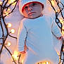Naël participe au concours pour gagner de l'argent avec cette photo : baby, infant, santa_hat, christmas_lights, fairy_lights, blanket, white_outfit, portrait, holiday, cozy, looking_up, face, eyes, cheeks, newborn, lying_down, festive, soft_texture, warm_glow, candid