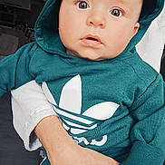 Naël participe au concours pour gagner de l'argent avec cette photo : baby, infant, child, hoodie, teal_hoodie, adidas_logo, logo, cute, big_eyes, wide_eyes, portrait, closeup, indoor, hand, adult_hand, holding, sweatshirt, casual_wear, expression, looking_at_camera