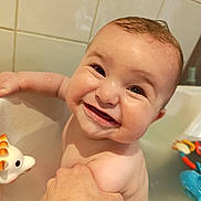 Naël participe au concours pour gagner de l'argent avec cette photo : adult_hand, baby, bath, bath_toy, bathroom, bathtub, cheeks, close_up, eyes, face, giraffe_toy, happy, holding, infant, portrait, smiling, tiles, toy, water, wet_skin