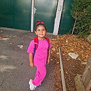Mady a rejoint le concours — aidez-le/la à gagner de superbes lots ! child, girl, pink_clothing, backpack, outdoor, path, autumn_leaves, green_gate, tree, sidewalk, casual, smiling, nature, daylight, footwear, hair_tie, standing, curly_hair, playful, park