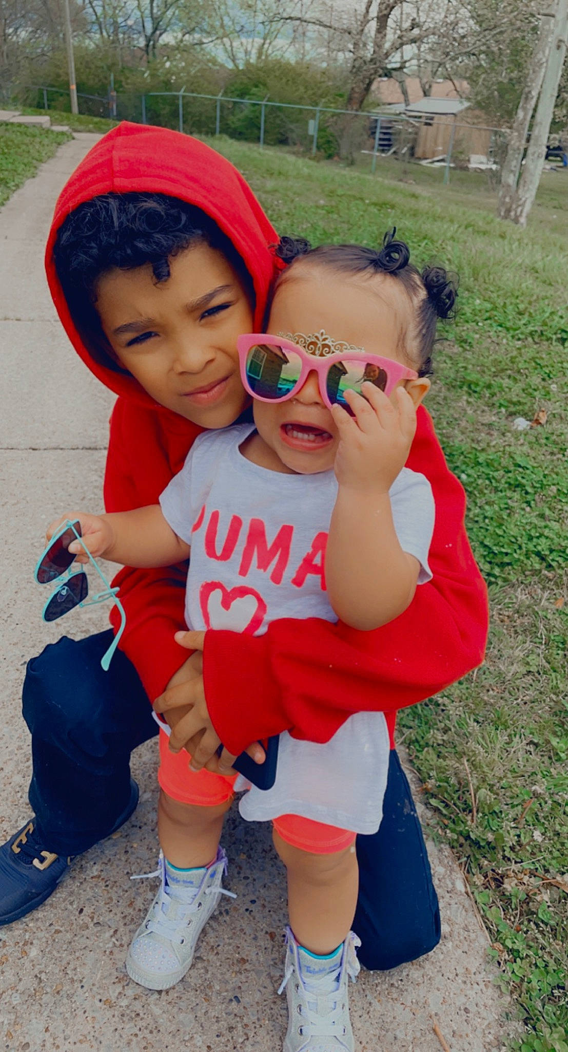 Alora is registered to the contest to win money with this photo: baby_toddler_clothing, eyewear, face, facial_expression, footwear, goggles, grass, happy, hat, leg, leisure, person, pink, plant, red, shoe, shorts, skin, sneakers, sunglasses