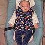 baby, infant, child, clothing, vest, hat, baby_seat, blue, space_theme, stars, rockets, furniture, blanket, pillow, cute, portrait, indoor, hands, footwear, expression