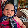 baby, child, face, headscarf, pink_clothing, indoor, couch, person, portrait, young_child, cute, curious, closeup, home_interior, furniture, soft_lighting, infant, comfortable, sitting, young_face