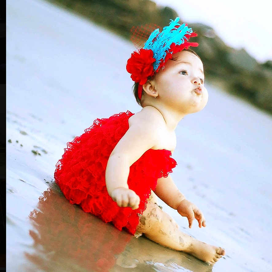 Camila joined the competition — help win amazing prizes! baby, child, red_dress, headband, feathers, beach, sand, water, sitting, cute, portrait, outdoor, infant, funny_face, pouting, photography_watermark, nature, holiday, summer, playful