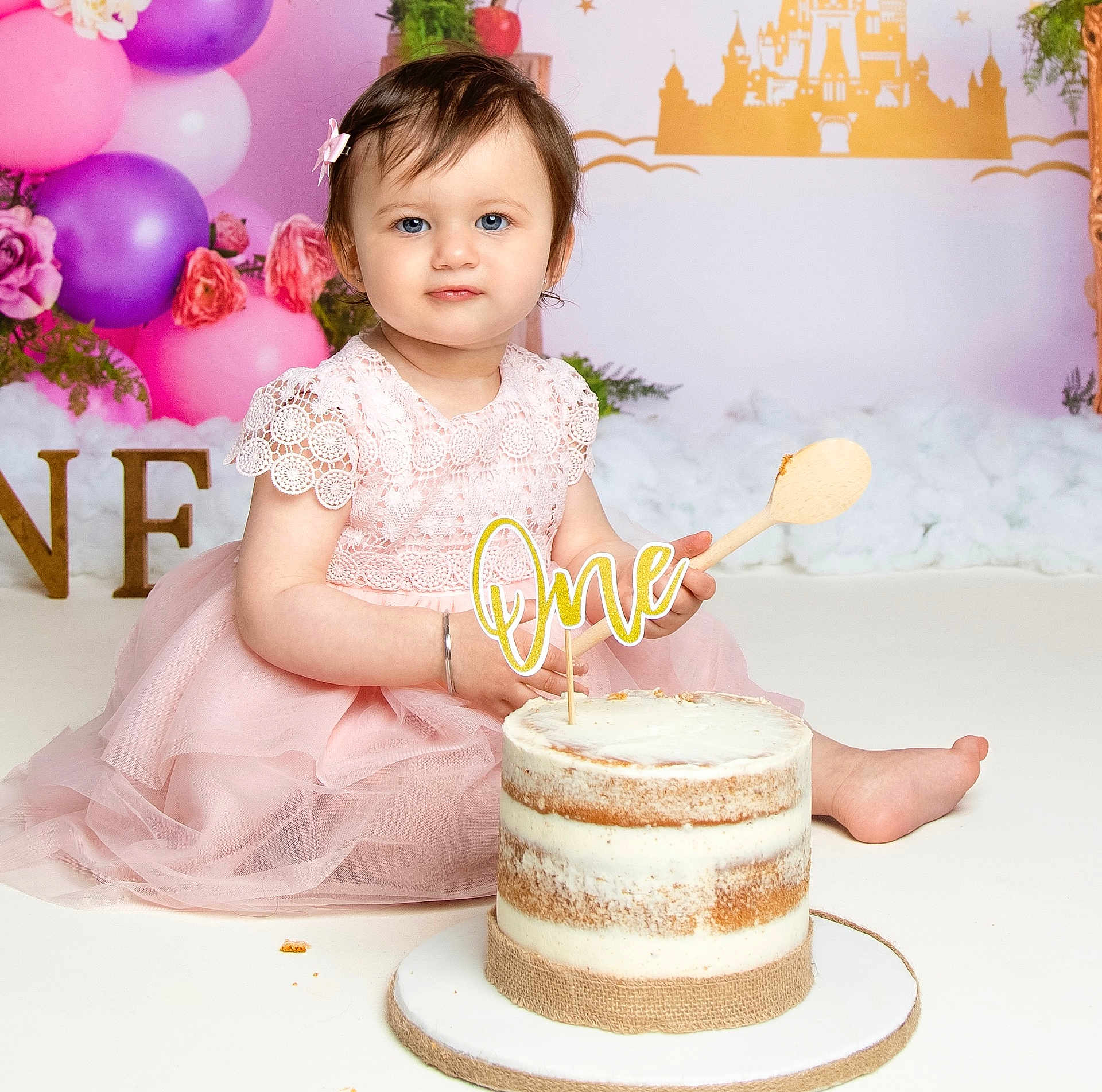 Niraya joined the competition — help win amazing prizes! baby, child, girl, birthday, cake, pink_dress, wooden_spoon, balloons, flowers, decorations, first_birthday, smiling, portrait, celebration, indoors, fairy_tale, castle_backdrop, sitting, cute, festive