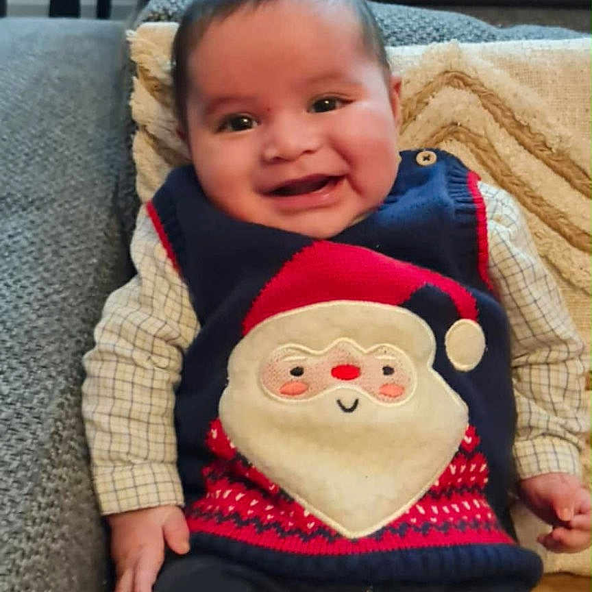 Fares Naël participe au concours pour gagner de l'argent avec cette photo : baby, blanket, cheerful, child, clothing, couch, cozy, face, festive, happy, head, holiday, indoor, jeans, person, red_socks, santa_claus, seated, smiling, sweater_vest