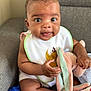 baby, infant, bib, stuffed_toy, couch, indoor, cute, child, smiling, seated, plush, person, happy, soft_toy, toddler, clothing, skin, hand, footwear, home