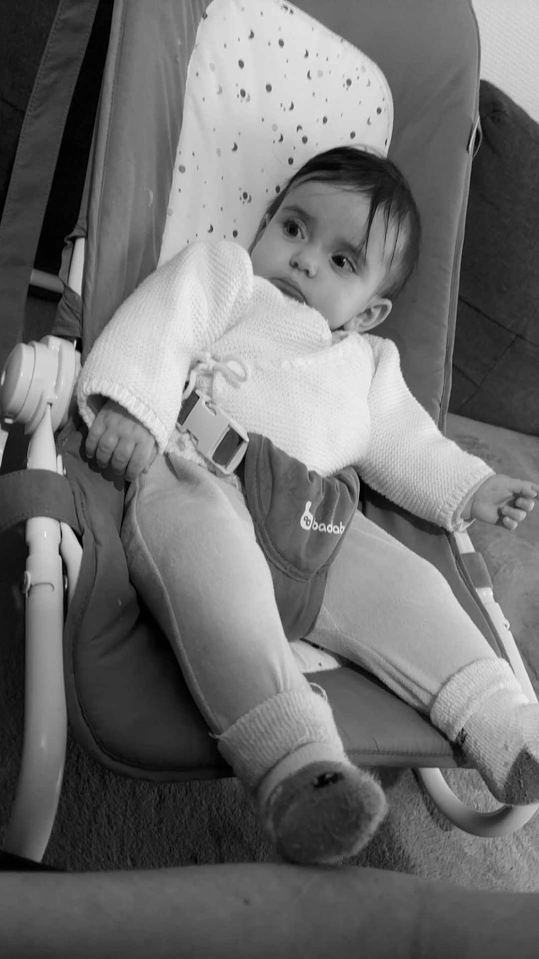 Ines participe au concours pour gagner de l'argent avec cette photo : baby, child, infant, baby_rocker, knitwear, socks, cushion, indoor, seated, face, person, portrait, black_and_white, relaxing, home, furniture, clothing, looking_away, young_child, cozy