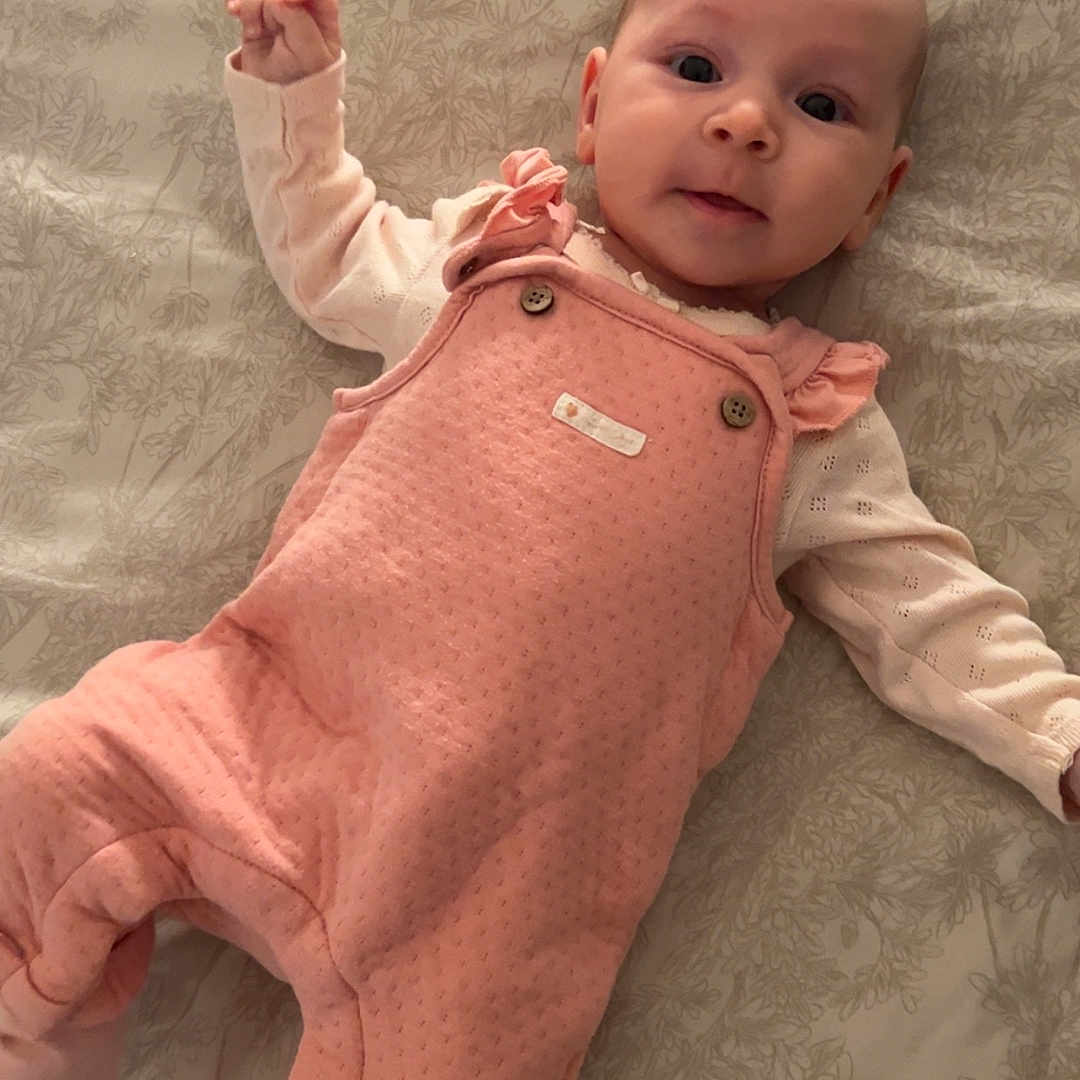 Alessia Canzonieri participe au concours pour gagner de l'argent avec cette photo : baby, bedspread, child, cozy_clothing, cute, expression, face, footed_pants, human, indoor, infant, looking_at_camera, lying_down, patterned_bedspread, pink_overall, portrait, small_hands, soft_light, white_shirt, young_child