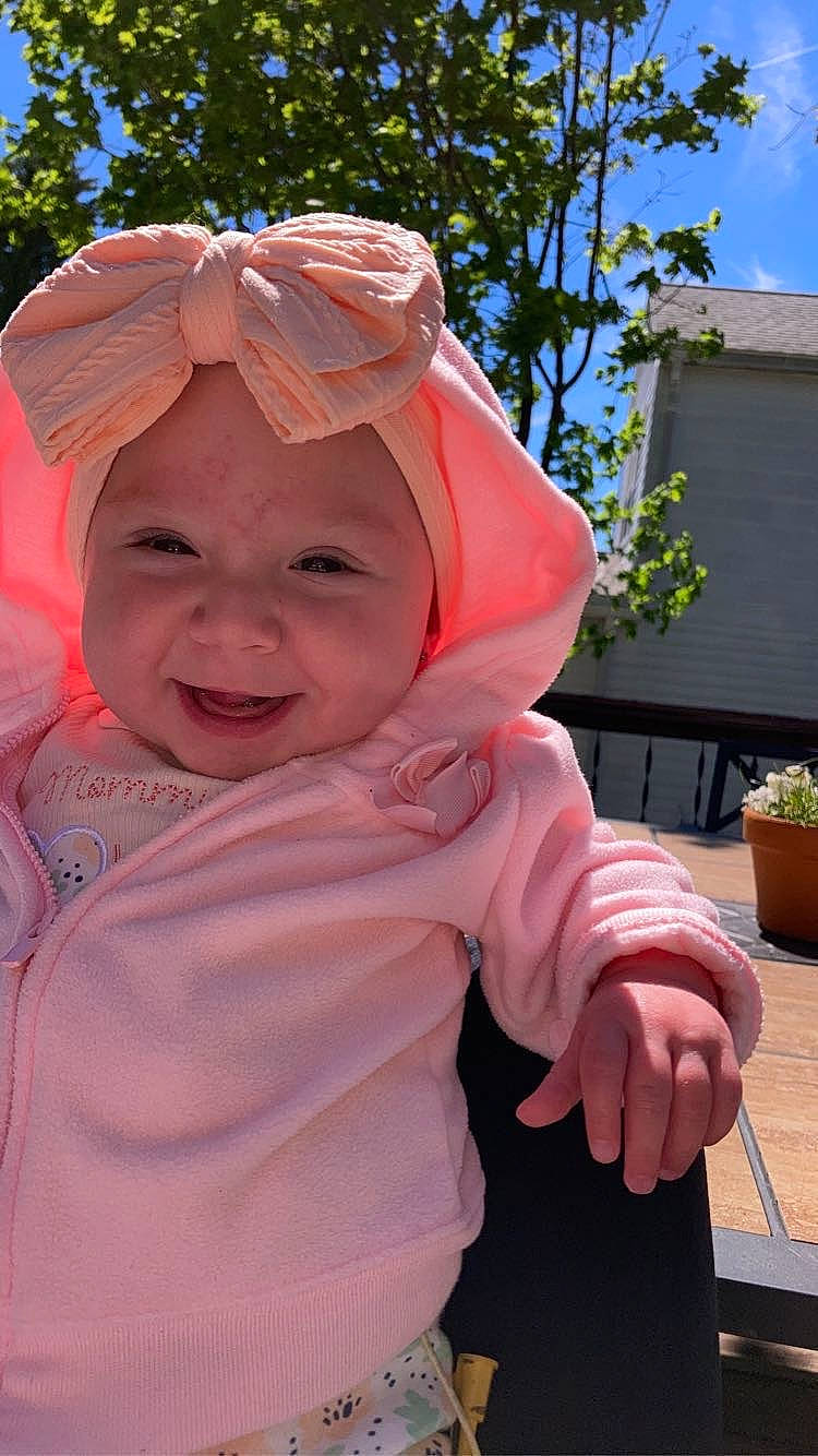 Joie is registered to the contest to win money with this photo: baby, baby_toddler_clothing, cap, child, fashion_accessory, flowerpot, fun, grass, happy, headwear, houseplant, joy, leisure, lip, magenta, person, pink, plant, recreation, sleeve