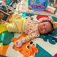 Milana joined the competition — help win amazing prizes! baby, cartoon_animals, child, colorful, cute, floor, floral_clothing, headband, indoor, infant, lying_down, mirror, mittens, play_area, play_mat, playtime, soft_light, toy, wooden_floor, yellow_pants