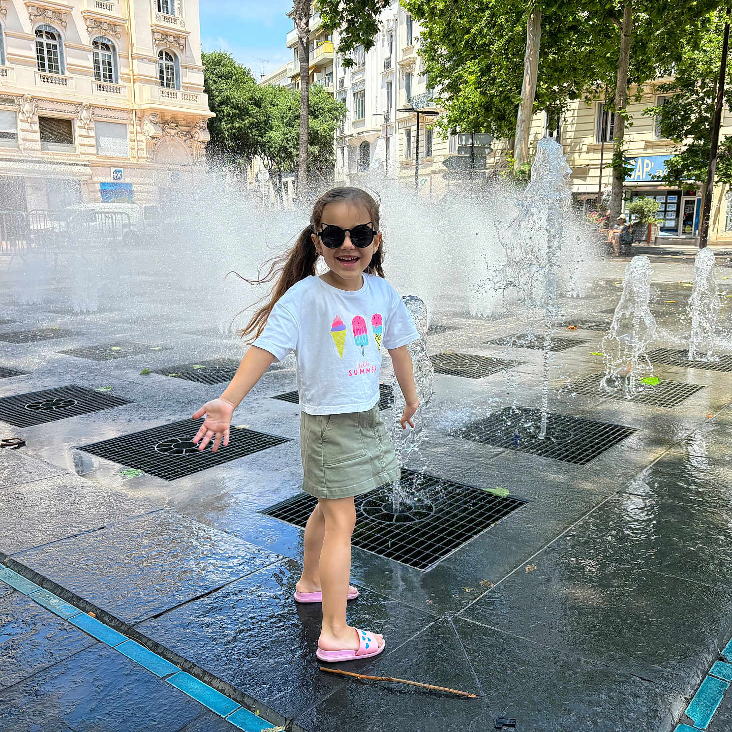 Alexandra a rejoint le concours — aidez-le/la à gagner de superbes lots ! accessories, architecture, child, city, clothing, face, female, fountain, girl, head, person, photography, portrait, road, shorts, street, sunglasses, t_shirt, urban, water