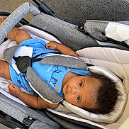Lydriss a rejoint le concours — aidez-le/la à gagner de superbes lots ! baby, child, stroller, blue_onesie, animal_print, gray, white, seatbelt, curly_hair, indoor, footwear, shoe, carrying_device, infant, person, looking_up, casual, texture, fabric, safety_harness