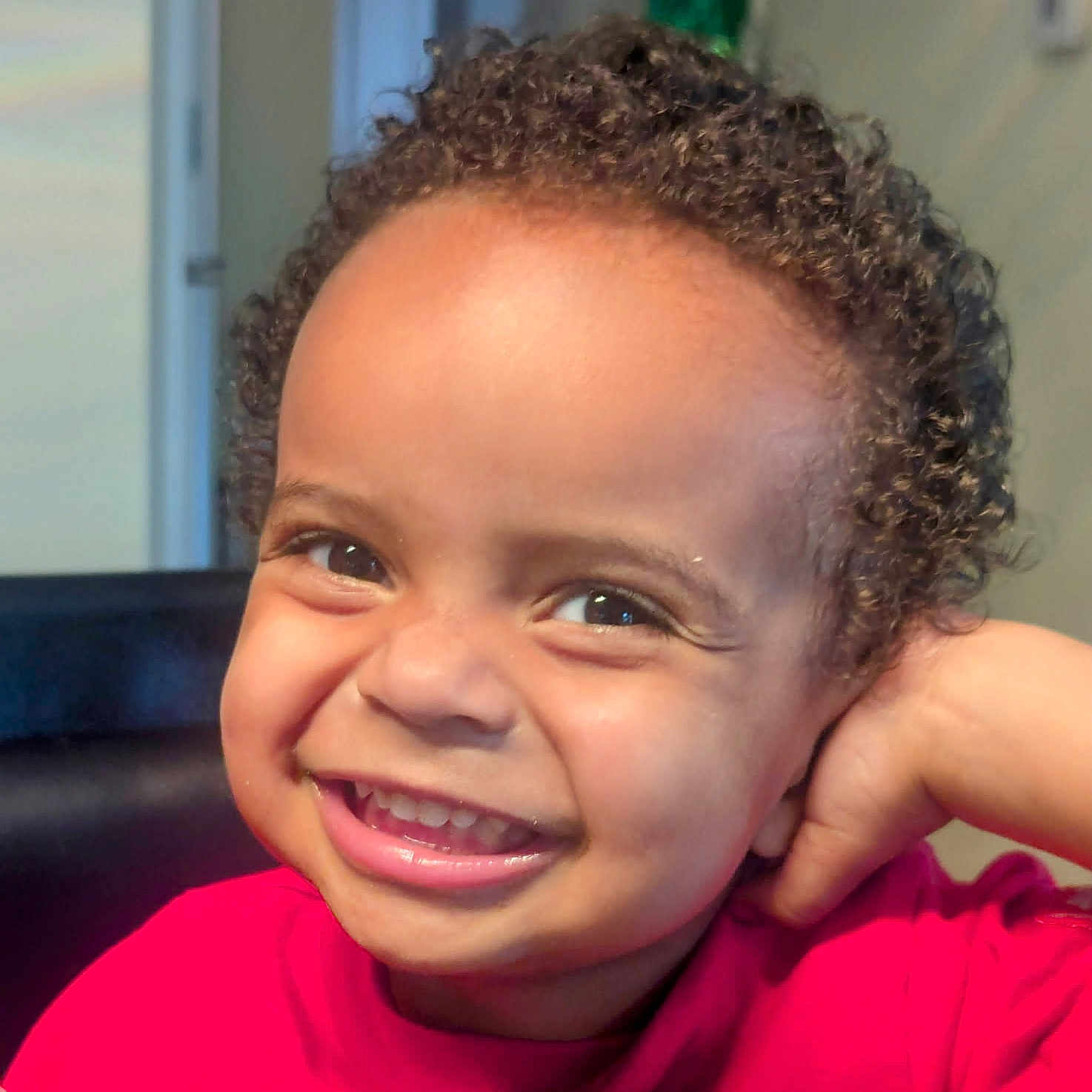 Micah is registered to the contest to win money with this photo: baby, bright, cheerful, child, closeup, curly_hair, cute, emotion, expression, face, happy, head, indoor, person, portrait, red_shirt, skin, smiling, toddler, young