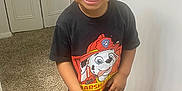 Micah is registered to the contest to win money with this photo: toddler, child, smile, indoor, black_tshirt, red_shorts, curly_hair, carpet, wood_floor, door, wall, sneakers, happy, standing, person, clothing, paw_patrol, marshall, cute, young_child
