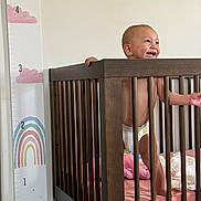 Zephyr joined the competition — help win amazing prizes! baby, crib, wooden_crib, smiling, standing, height_chart, rainbow, clouds, nursery, diaper, pink_bedding, toy, baby_room, child, infant, happy, indoor, furniture, person, home