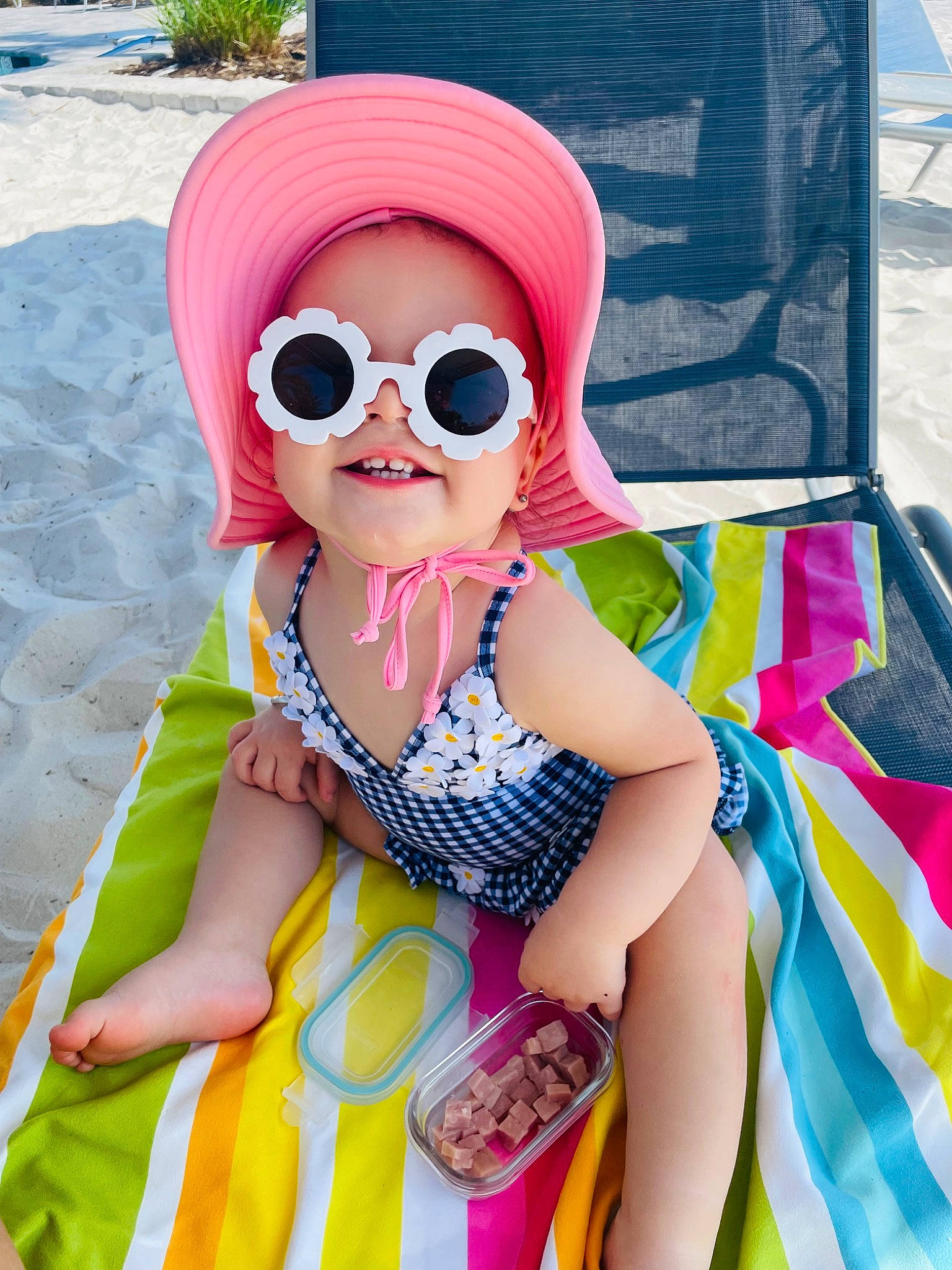 Berklee is registered to the contest to win money with this photo: baby_toddler_clothing, cap, child, electric_blue, eyewear, fun, glasses, goggles, happy, hat, leisure, magenta, pattern, person, personal_protective_equipment, pink, recreation, smile, sun_hat, sunglasses