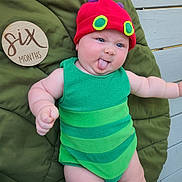 Truen joined the competition — help win amazing prizes! baby, child, infant, green_outfit, red_hat, tongue_out, cushion, plush, wooden_plaque, six_months, outdoor, person, cute, smiling, playful, skin, face, headwear, happy, portrait