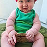Truen is registered to the contest to win money with this photo: baby, child, infant, smiling, green_outfit, red_hat, milestone_marker, sitting, cute, chubby, rosy_cheeks, indoor, blanket, hands, legs, face, portrait, happy, natural_light, skin