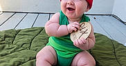 Truen joined the competition — help win amazing prizes! baby, infant, child, smiling, green_outfit, red_hat, plush_blanket, wooden_plaque, sitting, happy, indoors, cute, chubby, feet, hands, face, blue_eyes, hat, floor, wall