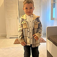 Christofer participe au concours pour gagner de l'argent avec cette photo : child, boy, indoor, plaid_jacket, pants, smile, standing, wardrobe, window, rug, floor, door, light, clothing, person, portrait, home, young, casual, cozy