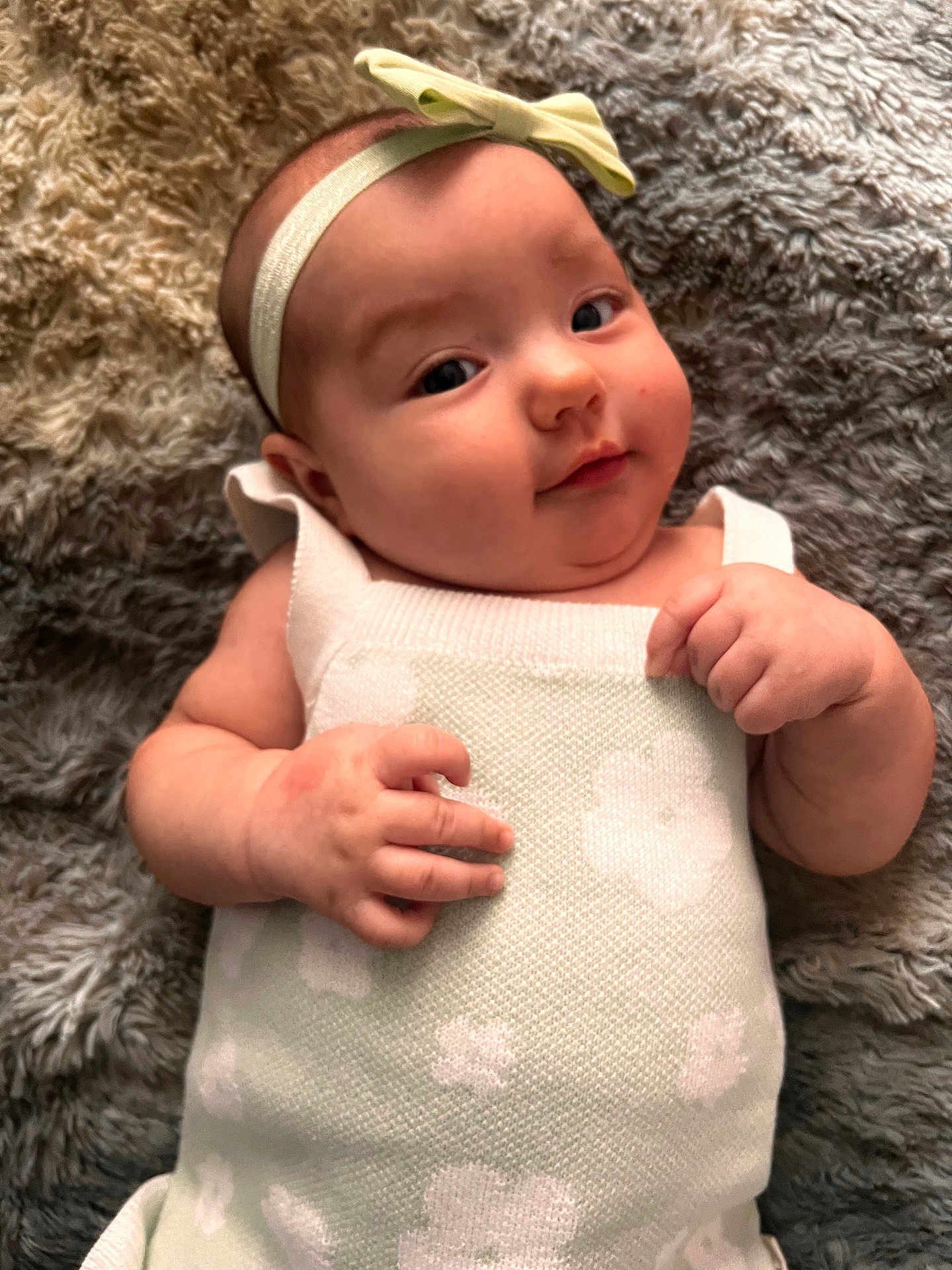 Arden is registered to the contest to win money with this photo: baby, infant, headband, bow, blanket, knitted_dress, flower_pattern, skin, hand, face, cheeks, lying_down, soft_texture, cute, portrait, young_child, indoors, cozy, relaxed, person