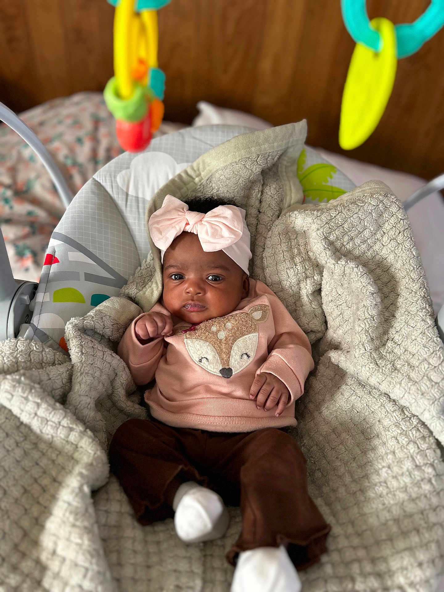 Reumani joined the competition — help win amazing prizes! baby, baby_seat, blanket, brown_pants, child, colorful, cozy, cute, dangle, fox_design, headband, indoor, infant, portrait, relaxed, soft_texture, sweater, toy, white_socks, wooden_background