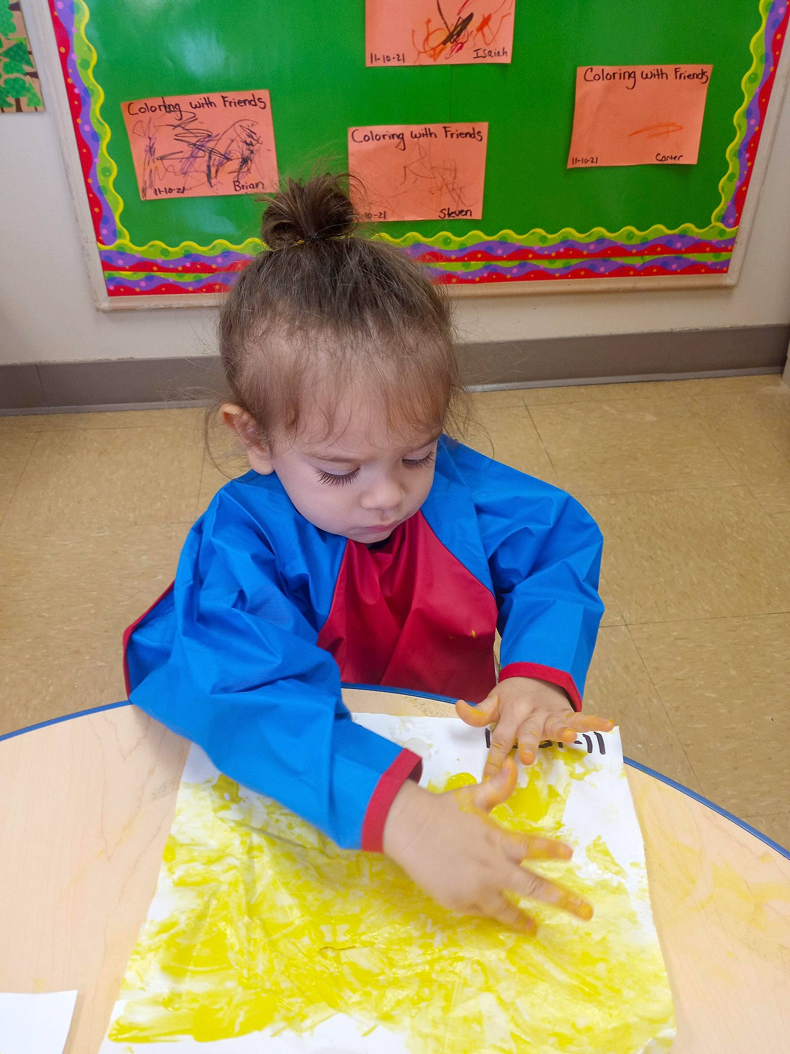 Azarel is registered to the contest to win money with this photo: chair, child, education, event, flooring, fun, kindergarten, learning, person, picture_frame, play, room, school, sharing, sitting, t_shirt, table, toddler, visual_arts, writing