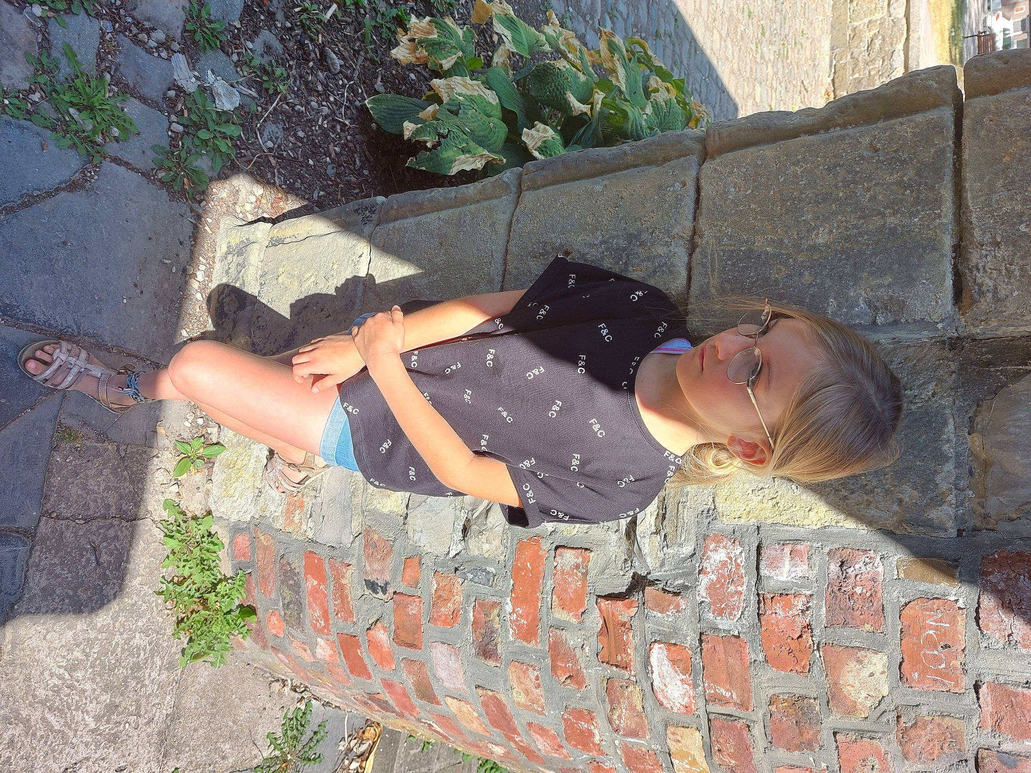 Mya a rejoint le concours — aidez-le/la à gagner de superbes lots ! asphalt, brick, brickwork, cobblestone, concrete, eyewear, grass, human_leg, knee, leisure, pattern, people_in_nature, person, plant, road_surface, sandal, shadow, sidewalk, sitting, thigh