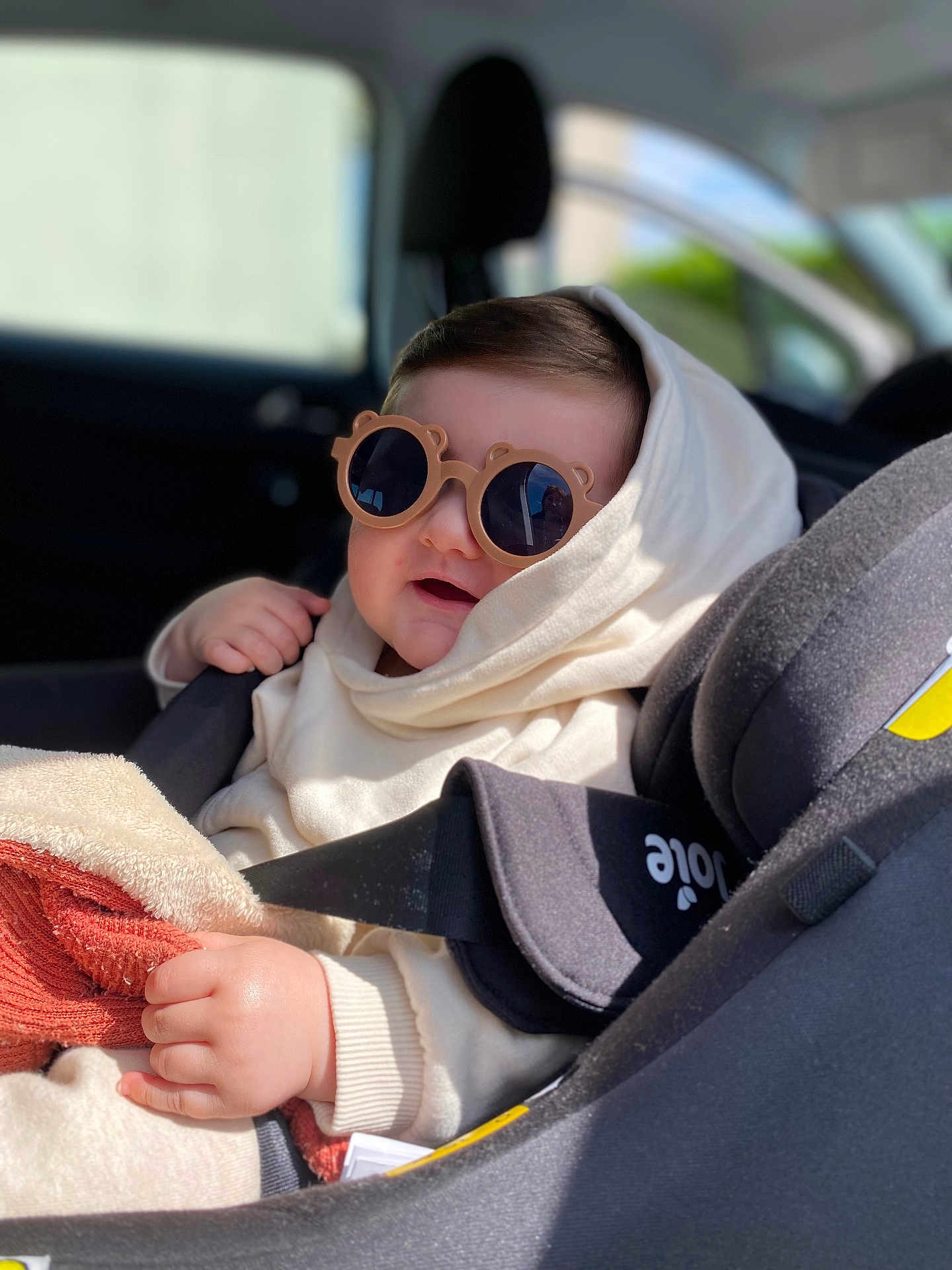 Emin a rejoint le concours — aidez-le/la à gagner de superbes lots ! baby, child, car_seat, sunglasses, hoodie, blanket, hand, face, smiling, seatbelt, indoor, car_interior, cozy, cute, sunlight, portrait, infant, clothing, seat, person