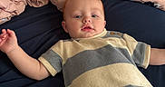 Howard is registered to the contest to win money with this photo: baby, child, infant, portrait, lying_down, bed, blanket, bedding, pink, patterned, striped_shirt, clothing, blue, eyes_open, facial_expression, indoor, home, close_up, arms_outstretched, photography