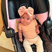 Carlota joined the competition — help win amazing prizes! baby, infant, car_seat, headband, bow, smile, clothing, pink, peach, black, seatbelt, infant_wear, footwear, cute, child, indoors, car_seat_cover, person, sitting, adorable