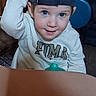 Joshua is registered to the contest to win money with this photo: blue_eyes, cap, casual, chair, child, clothing, curious, cushion, face, hand, hat, indoor, pacifier, person, portrait, sitting, table, toddler, wood, young_child