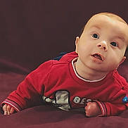 Tiyler participe au concours pour gagner de l'argent avec cette photo : baby, background, casual_clothing, child, curious, cute, expression, face, head, indoors, infant, lying_down, open_mouth, portrait, red_sweater, skin, small_hands, soft_surface, wide_eyes, young_child