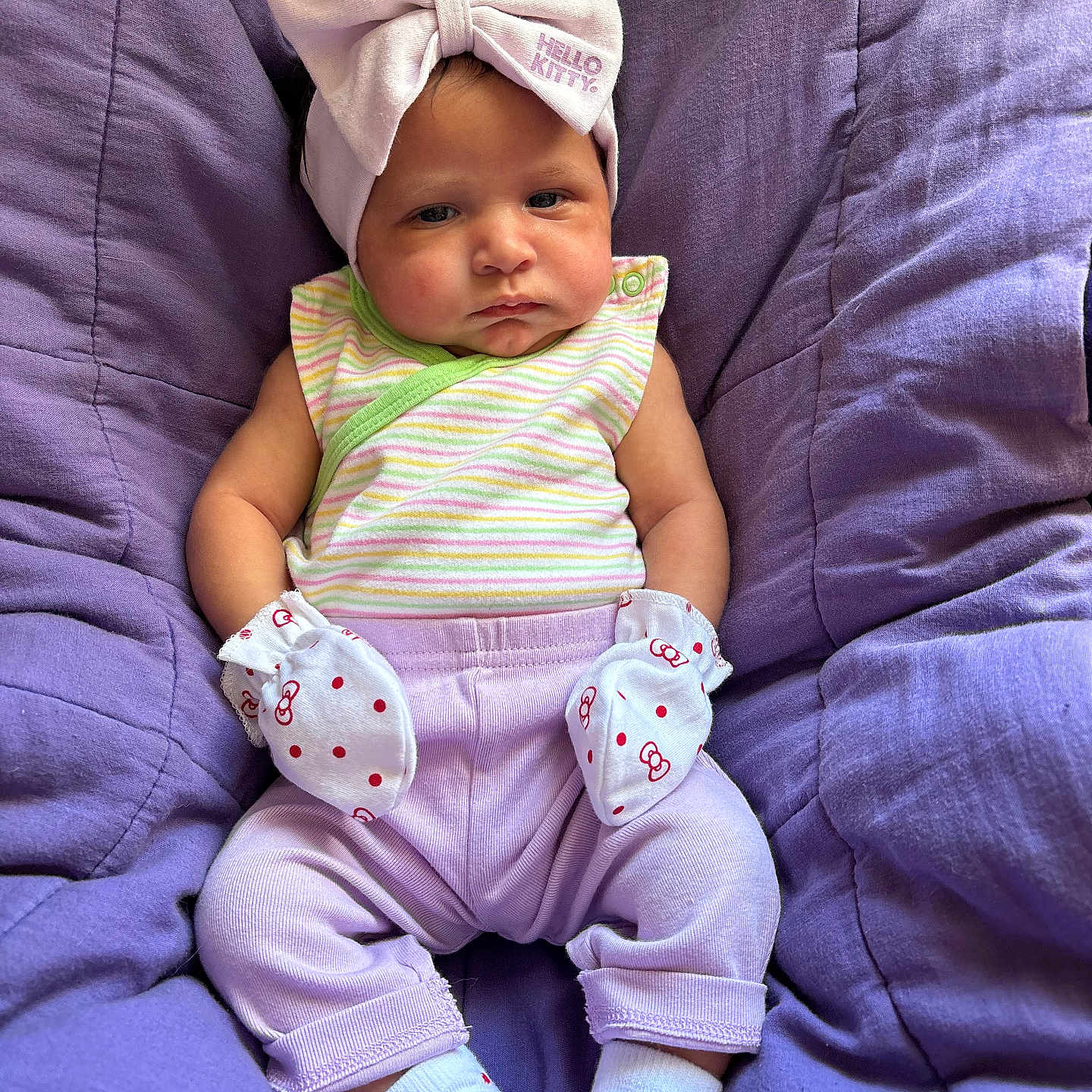 Kehlani is registered to the contest to win money with this photo: baby, casual, child, comfortable, cute, expression, headband, hello_kitty, indoor, infant, mittens, pastel_colors, plush, portrait, purple_cushion, seated, socks, soft_texture, striped_clothing, young_baby