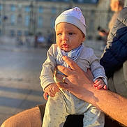 Bato a rejoint le concours — aidez-le/la à gagner de superbes lots ! baby, child, infant, person, human_hand, clothing, hat, adult_hand, outdoor, sunlight, portrait, holding, warm_light, blurred_background, face, expression, casual, daytime, people, urban