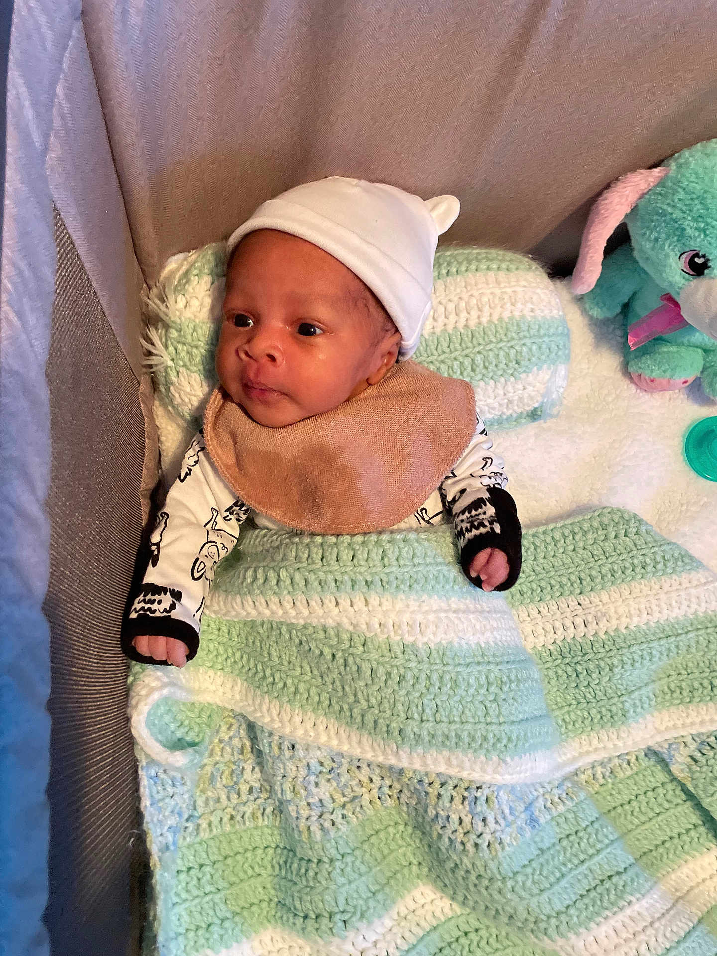 Chozen is registered to the contest to win money with this photo: baby, infant, crib, blanket, knit, hat, plush_toy, rabbit, pacifier, clothing, soft_texture, child, cute, indoors, portrait, sleeping_area, headwear, person, resting, cozy