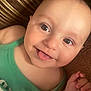 baby, child, face, tongue_out, green_clothing, close_up, smiling, cute, skin, hand, infant, portrait, eyes, expression, lying_down, one_person, indoors, playful, happy, baby_skin