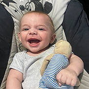 Joshua is registered to the contest to win money with this photo: baby, smiling, teddy_bear, stuffed_toy, mickey_mouse, cushion, chair, child, happy, infant, clothing, face, arm, hand, indoor, portrait, cute, playful, relaxed, seat