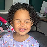 Mila-Ivy is registered to the contest to win money with this photo: child, curly_hair, purple_shirt, popsicle_print, smiling, squinting, indoors, toy, play_area, happy, cute, casual, portrait, kid, person, toddler, earrings, home, fun, colorful