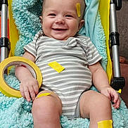 Devin is registered to the contest to win money with this photo: baby, infant, stroller, blanket, tape, roll_of_tape, yellow_tape, blue_blanket, smiling, onesie, striped_clothing, legs, feet, hand, chubby_legs, indoor, cozy, seat, happy, portrait