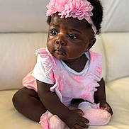 Anaya joined the competition — help win amazing prizes! baby, infant, child, girl, pink_headband, pink_outfit, sitting, curious, cute, portrait, indoors, couch, soft_lighting, flower_headband, sock, dark_skin, short_hair, earring, closeup, person