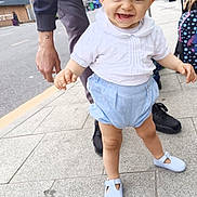 Rowan is registered to the contest to win money with this photo: toddler, child, smiling, walking, sidewalk, urban, adult, hand, white_shirt, blue_shorts, baby_shoes, outdoor, daylight, person, street, happiness, cute, support, city, casual_clothing