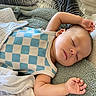 James is registered to the contest to win money with this photo: baby, sleeping, blanket, blue_checkered, infant, child, peaceful, soft_texture, relaxing, resting, cute, indoors, toddler, skin, head, arm, hand, clothing, face, cozy